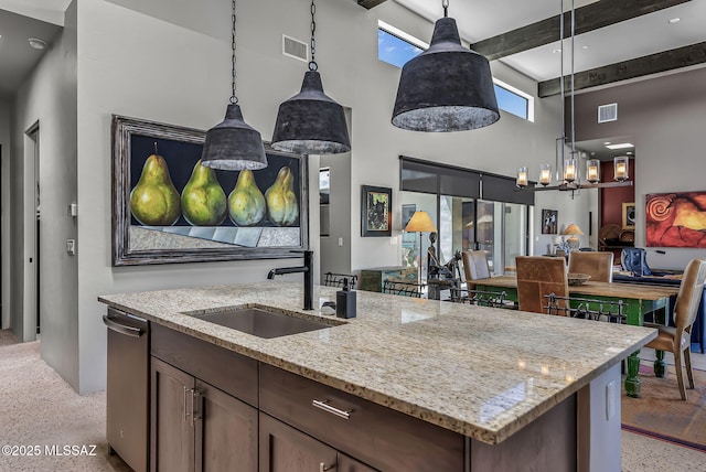 kitchen featuring a sink, dishwasher, a kitchen island with sink, open floor plan, and a towering ceiling