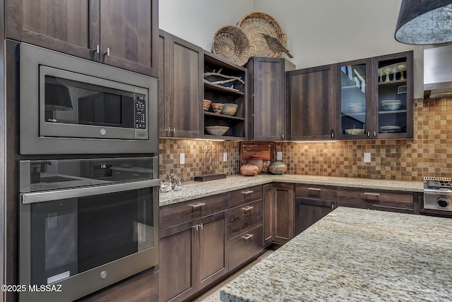kitchen with light stone counters, decorative backsplash, appliances with stainless steel finishes, and dark brown cabinetry