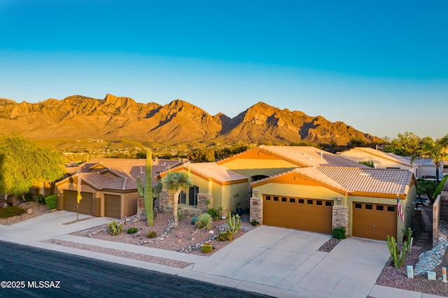 view of front of property featuring stucco siding, driveway, a tile roof, and a garage