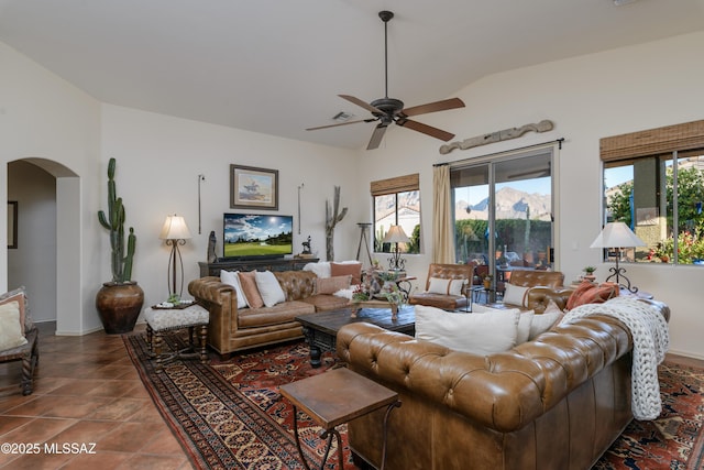 living area featuring arched walkways, baseboards, a ceiling fan, and vaulted ceiling