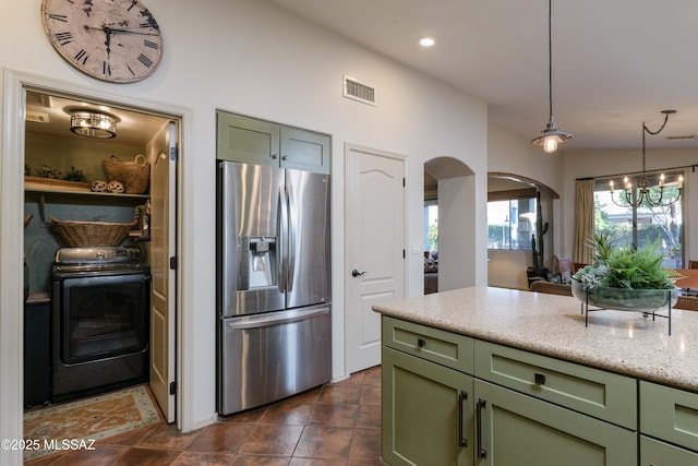 kitchen with stainless steel refrigerator with ice dispenser, washer / clothes dryer, and green cabinets