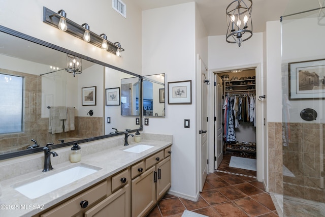 full bath with a sink, tile patterned floors, visible vents, and a chandelier