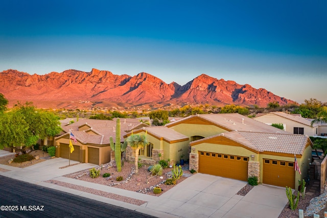 view of front of home featuring driveway, a mountain view, a tile roof, and a garage