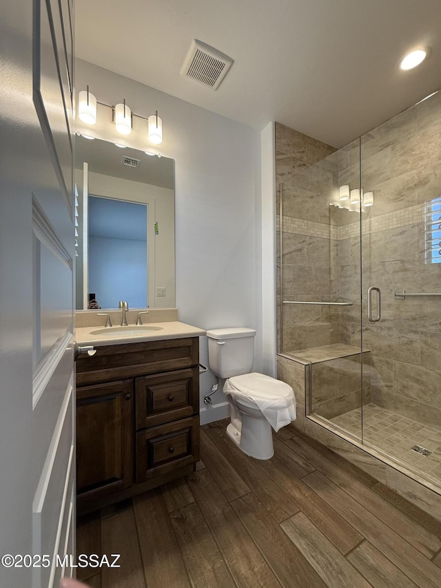 66414 E Peregrine Pl, Tucson, AZ 85739 - bathroom featuring wood finished floors, toilet, vanity, a stall shower, and recessed lighting