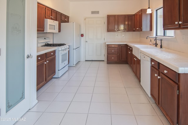 kitchen featuring decorative light fixtures, visible vents, tasteful backsplash, tile counters, and white appliances