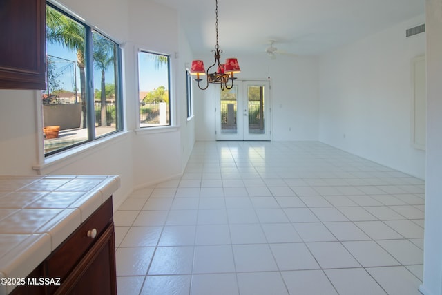 unfurnished dining area with visible vents, light tile patterned floors, a wealth of natural light, and french doors