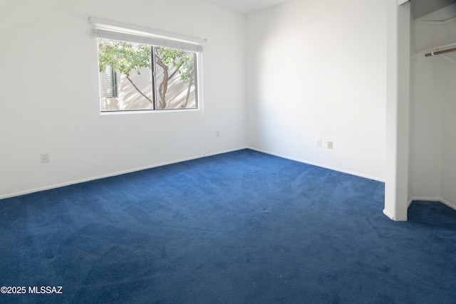 unfurnished bedroom featuring baseboards, dark carpet, and a closet
