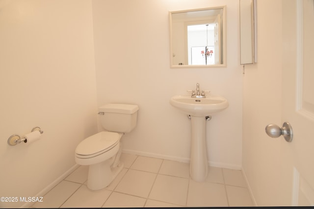 bathroom featuring baseboards, tile patterned floors, and toilet