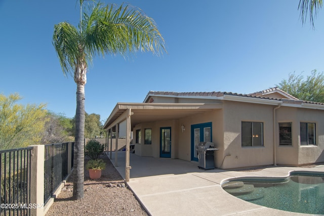 rear view of property with a fenced in pool, fence, stucco siding, and an attached carport