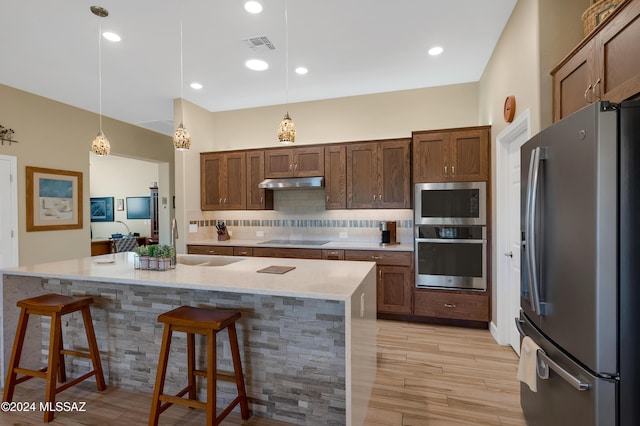 62911 E Thunder Rock Dr, Saddlebrooke, AZ 85739 - kitchen featuring appliances with stainless steel finishes, under cabinet range hood, a sink, decorative backsplash, and a kitchen breakfast bar