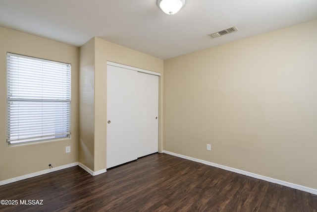 4249 E Cholla Desert Trl, Tucson, AZ 85706 - unfurnished bedroom featuring dark wood finished floors, multiple windows, a closet, and baseboards