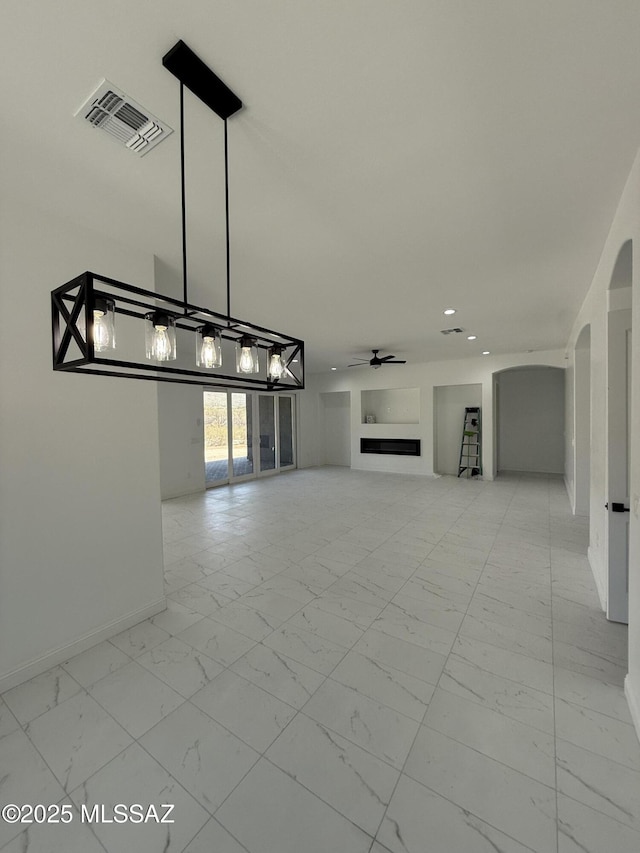 unfurnished living room with arched walkways, marble finish floor, ceiling fan, a fireplace, and visible vents