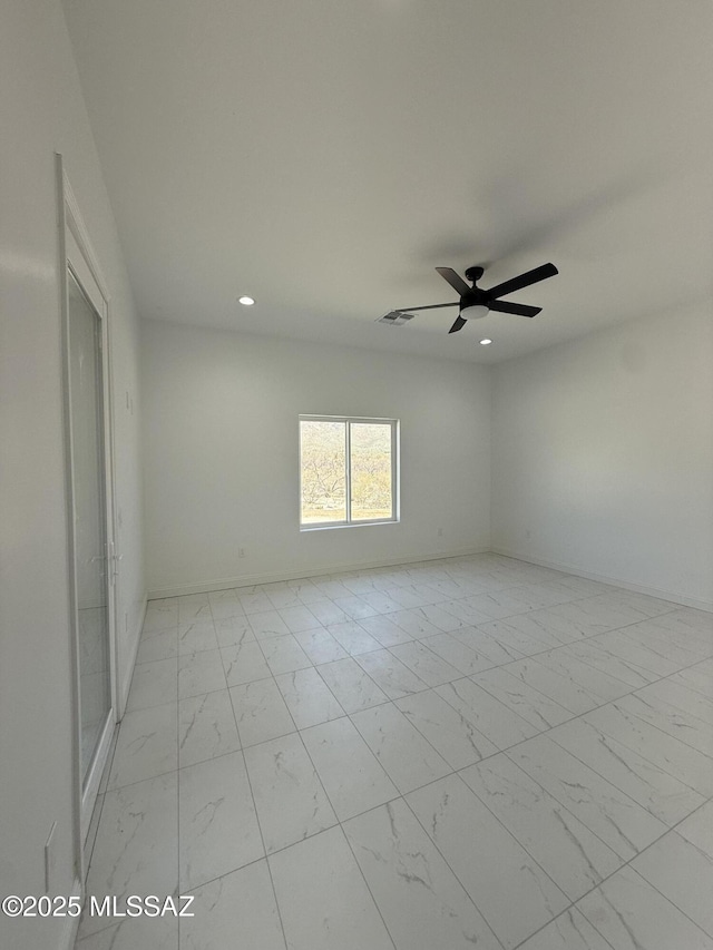 spare room featuring ceiling fan, recessed lighting, marble finish floor, and baseboards