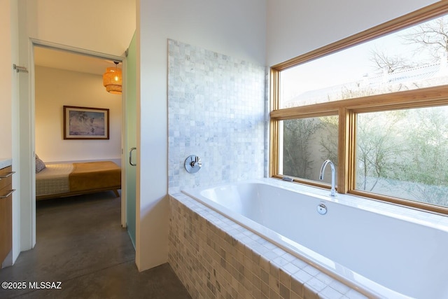 bathroom featuring concrete floors, ensuite bathroom, and a bath
