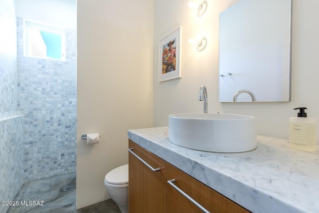 full bath featuring toilet, tiled shower, and vanity