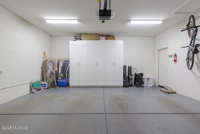 garage featuring a garage door opener and concrete block wall