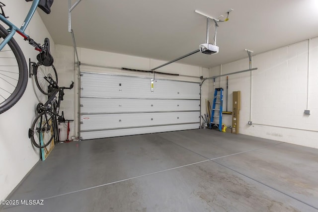 garage featuring concrete block wall and a garage door opener