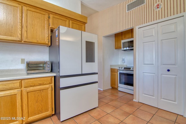 4050 S Melpomene Way, Tucson, AZ 85730 - kitchen with freestanding refrigerator, a toaster, light tile patterned flooring, light countertops, and stainless steel electric range oven