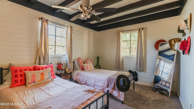 carpeted bedroom featuring beam ceiling, brick wall, and multiple windows