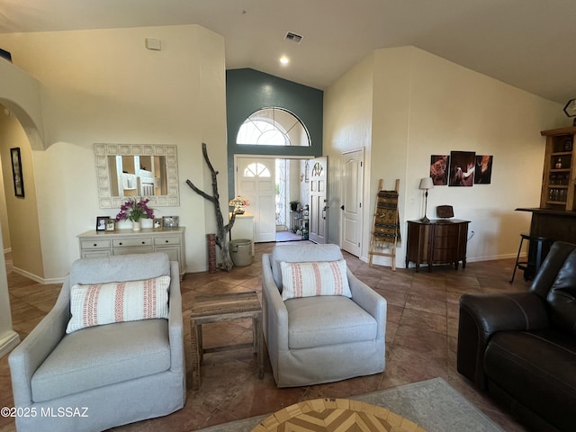 living area with high vaulted ceiling, baseboards, arched walkways, and visible vents
