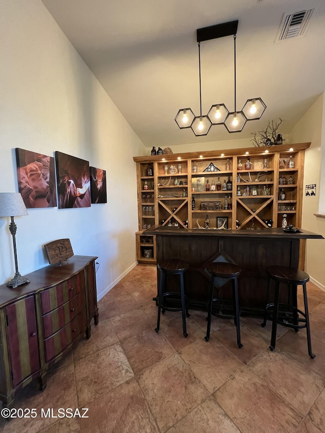 wine room featuring baseboards, a dry bar, lofted ceiling, and visible vents