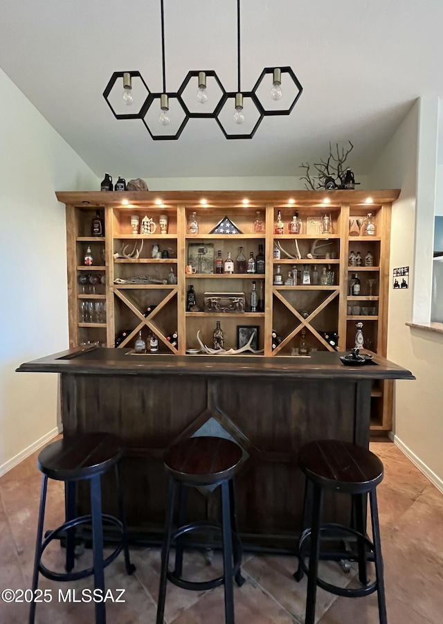 bar featuring baseboards and a bar
