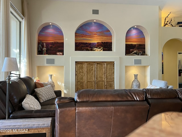 living area featuring arched walkways and a healthy amount of sunlight