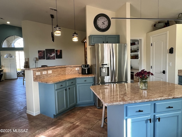 kitchen with stainless steel refrigerator with ice dispenser, a center island, light stone counters, hanging light fixtures, and blue cabinetry