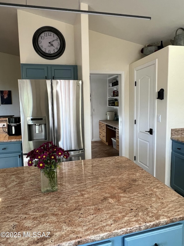 kitchen featuring light countertops, blue cabinetry, stainless steel refrigerator with ice dispenser, and lofted ceiling
