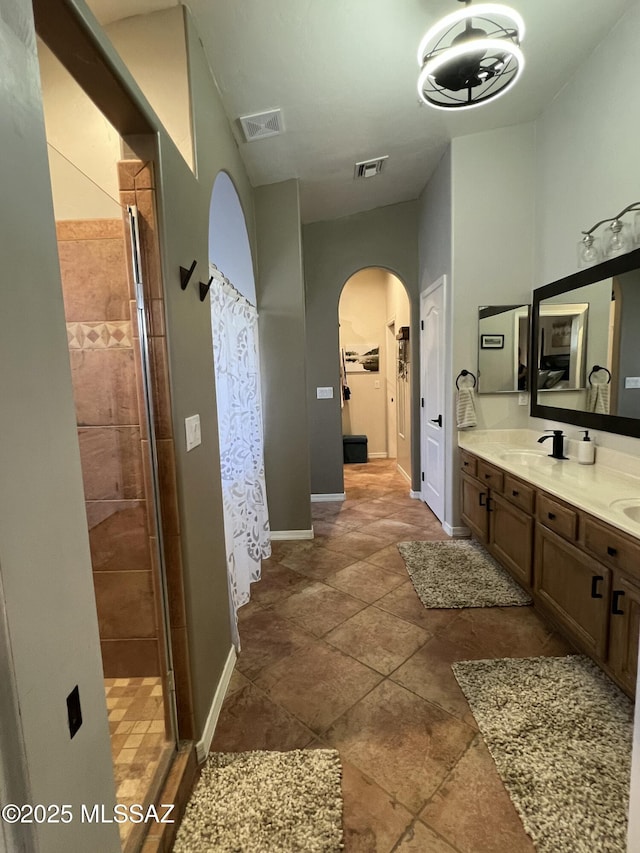 full bathroom featuring visible vents, a sink, double vanity, and a shower stall