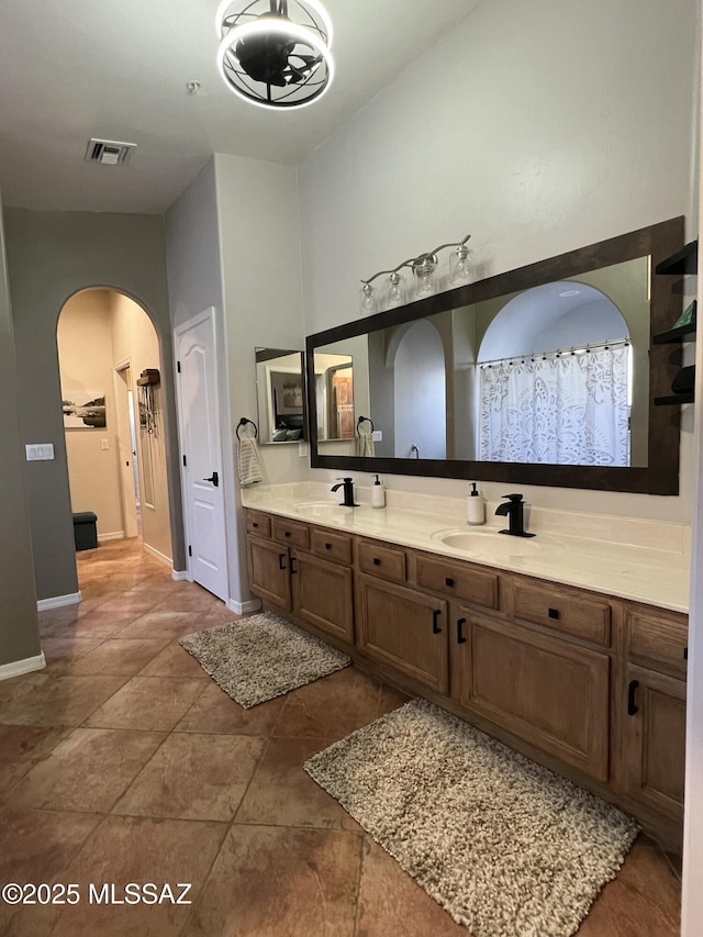 full bathroom with a sink, baseboards, double vanity, and visible vents
