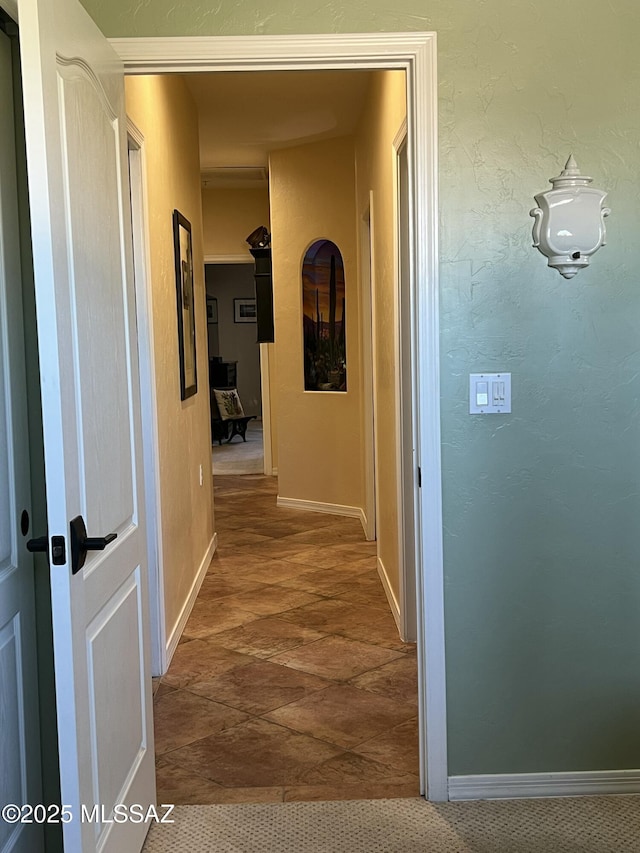 hallway with baseboards and stone finish floor
