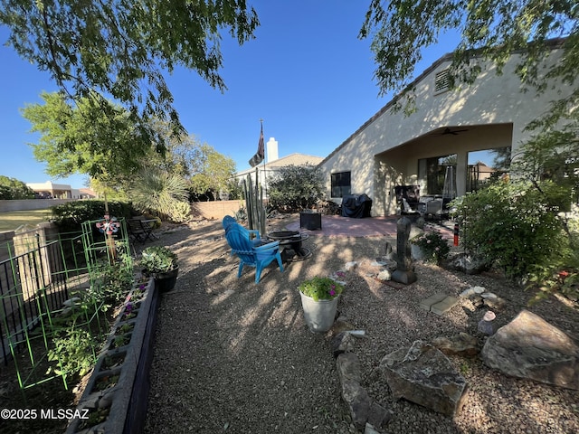 view of yard with a patio, ceiling fan, a fenced backyard, and an outdoor fire pit