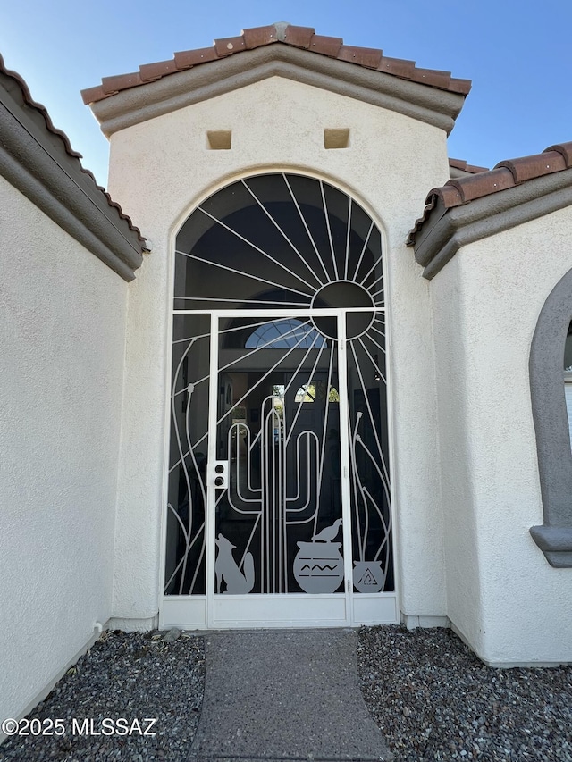 entrance to property featuring a tile roof and stucco siding