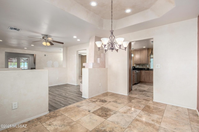 interior space with a raised ceiling, ceiling fan with notable chandelier, recessed lighting, baseboards, and visible vents