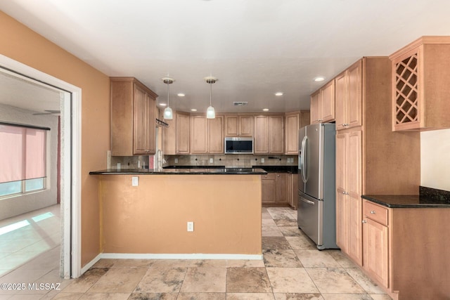kitchen featuring a peninsula, tasteful backsplash, dark countertops, and stainless steel appliances