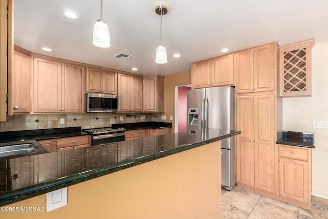 kitchen with backsplash, visible vents, appliances with stainless steel finishes, a sink, and dark stone countertops