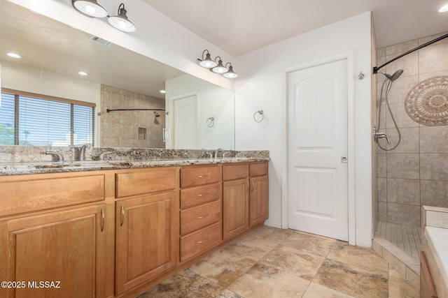 full bathroom featuring double vanity, a sink, visible vents, and tiled shower
