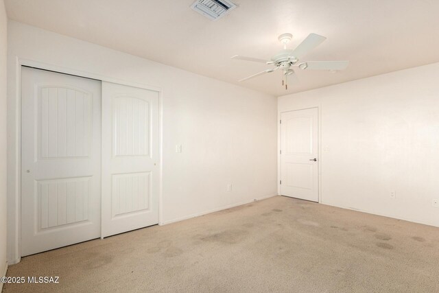 empty room with carpet floors, baseboards, a ceiling fan, and visible vents