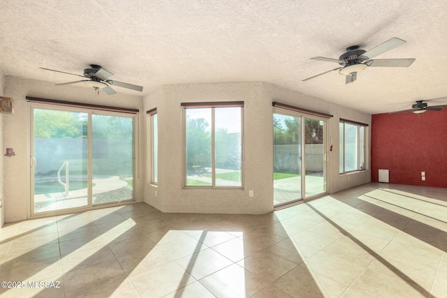 unfurnished sunroom with tile patterned floors, plenty of natural light, and a textured ceiling
