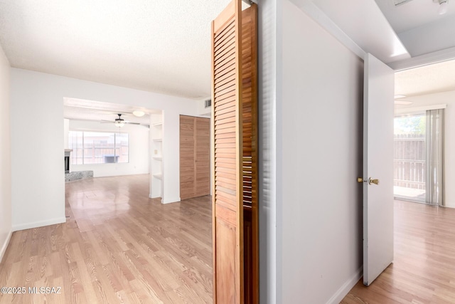 corridor featuring baseboards and light wood finished floors