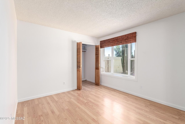 empty room with baseboards, a textured ceiling, and wood finished floors
