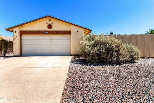 view of front of property featuring fence, stucco siding, and driveway