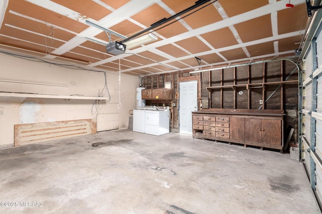 garage with washing machine and clothes dryer, water heater, and a garage door opener
