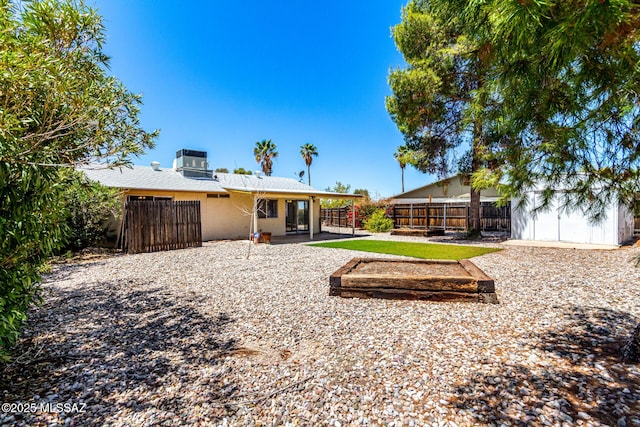 rear view of house with a patio, a fenced backyard, central AC unit, a storage shed, and an outbuilding