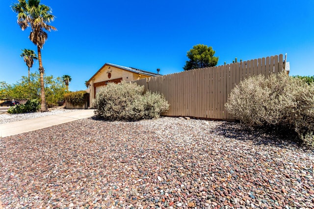 view of side of property with an attached garage and fence