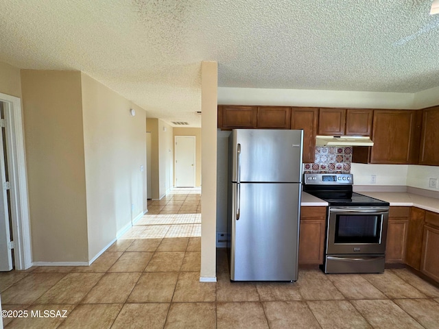 kitchen featuring brown cabinetry, light countertops, under cabinet range hood, and stainless steel appliances