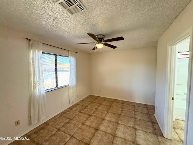 spare room featuring visible vents, a textured ceiling, ceiling fan, and baseboards