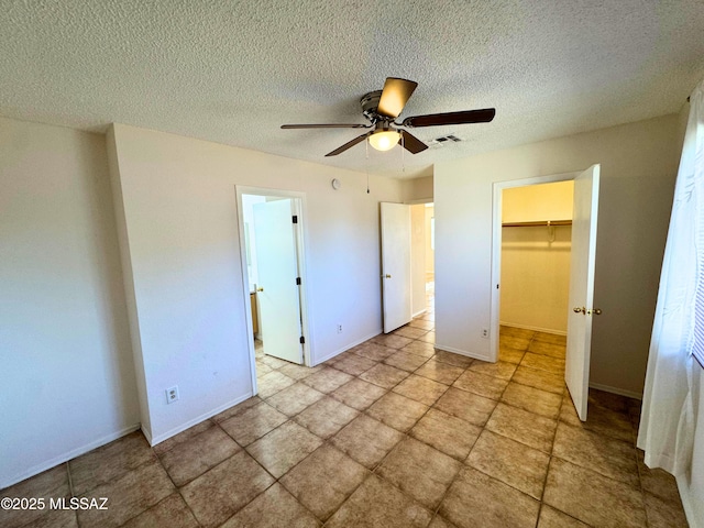 unfurnished bedroom with a textured ceiling, visible vents, a walk in closet, and a closet