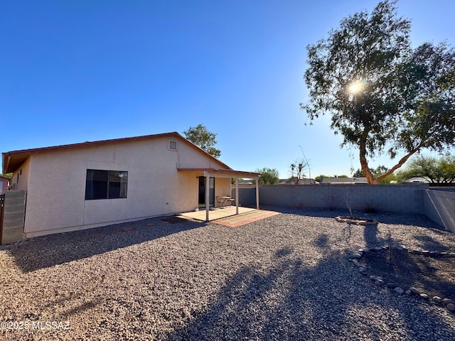 back of house featuring a fenced backyard, a patio, and stucco siding